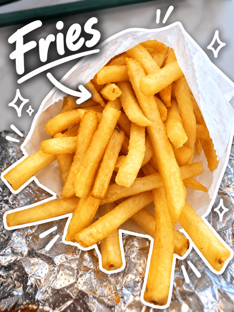 A serving of golden, crispy French fries in a paper bag, with a decorative hand-drawn design and the word 'Fries' highlighted above.