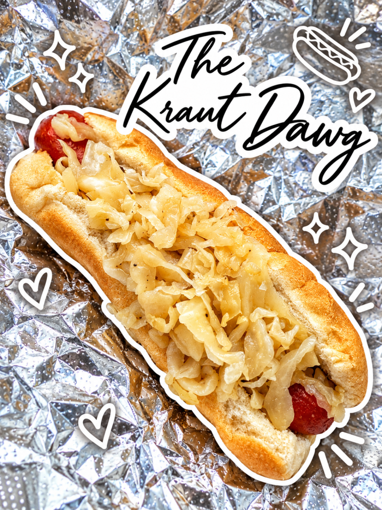 A close-up of a hot dog topped with sauerkraut, served in a light bun on a shiny foil background, with decorative text overlay reading 'The Kraut Dawg'.