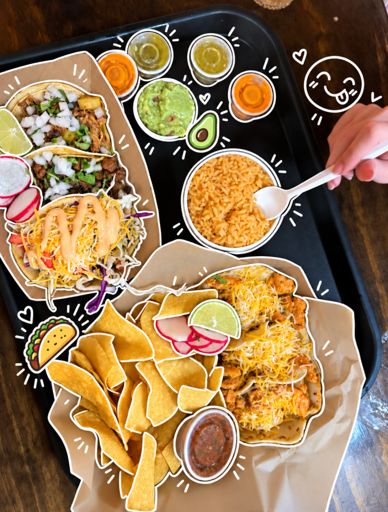 A delicious spread of tacos with meat and toppings, a side of rice, tortilla chips, and various sauces on a black tray, accompanied by a hand holding a spoon.