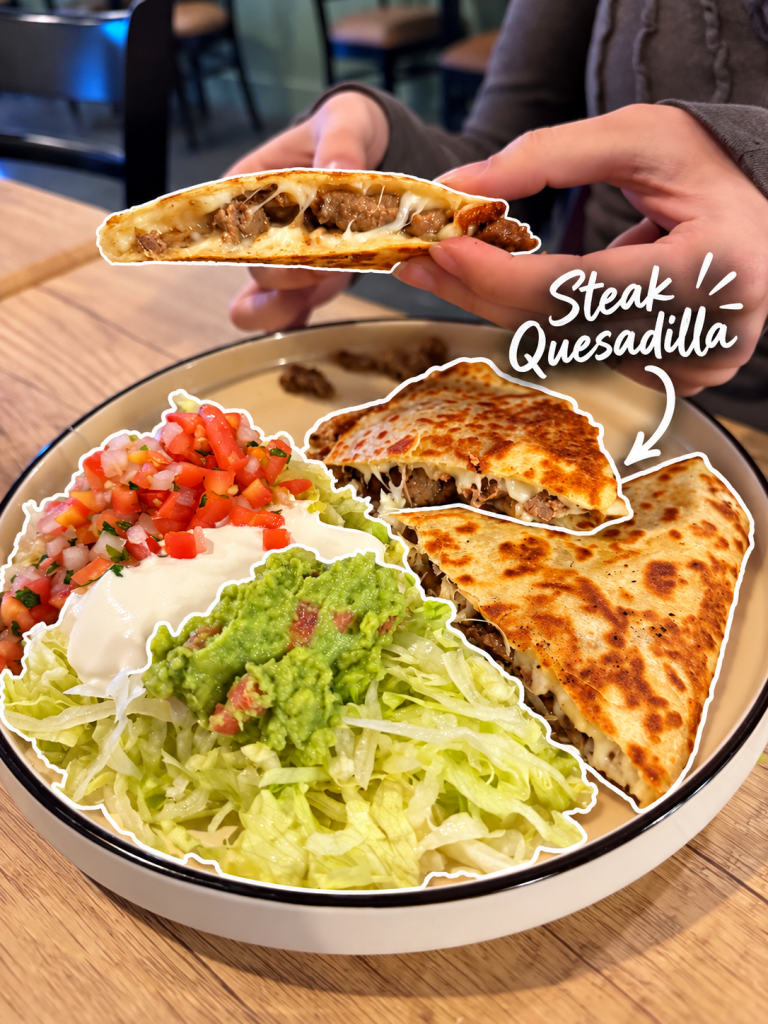 A close-up of a person holding a steak quesadilla, showing the melted cheese and beef filling. The plate includes lettuce, guacamole, sour cream, and pico de gallo.